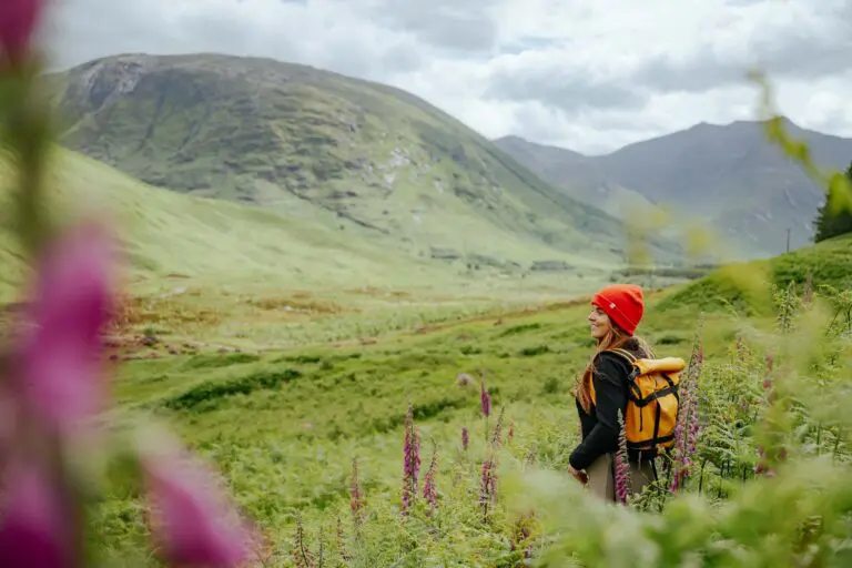 woman hiking in Scottish Highlands with red beanie and yellow backpack